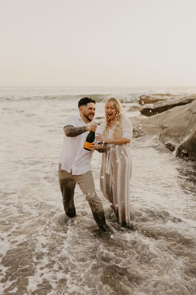 Couple popping champagne to celebrate their engagement.
