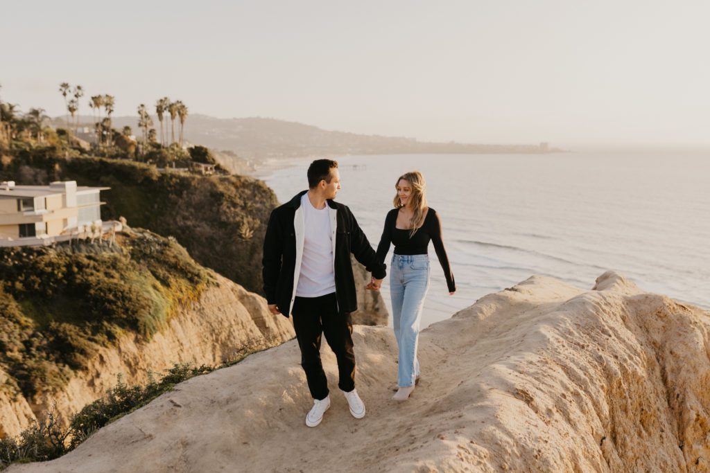couple walking along cliffs with the ocean in the background