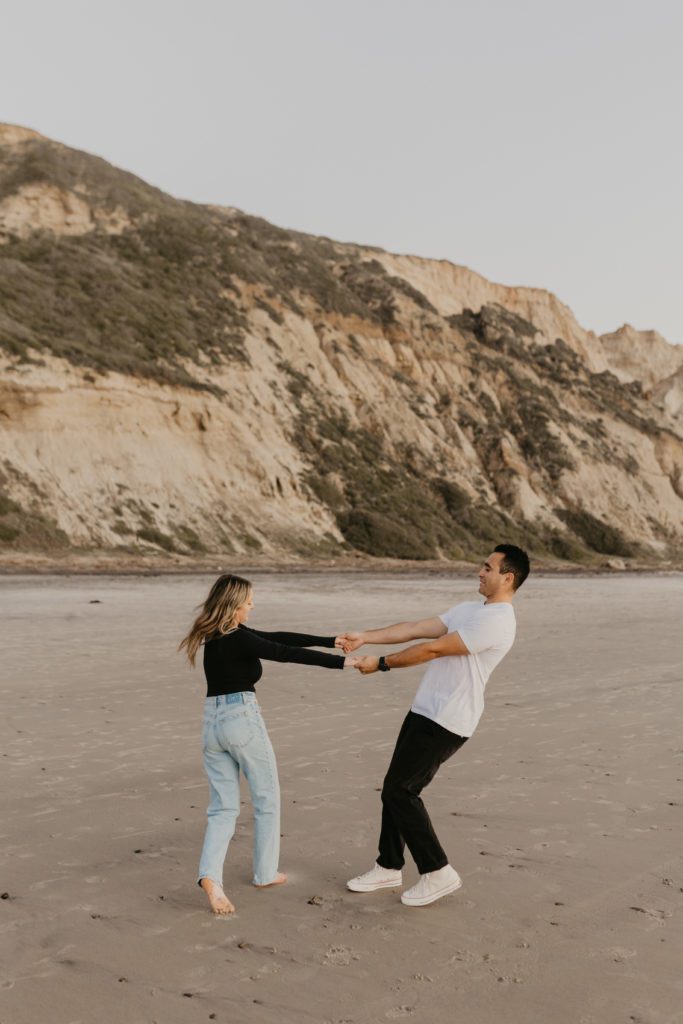 Couple spinning around on a beach in San Diego